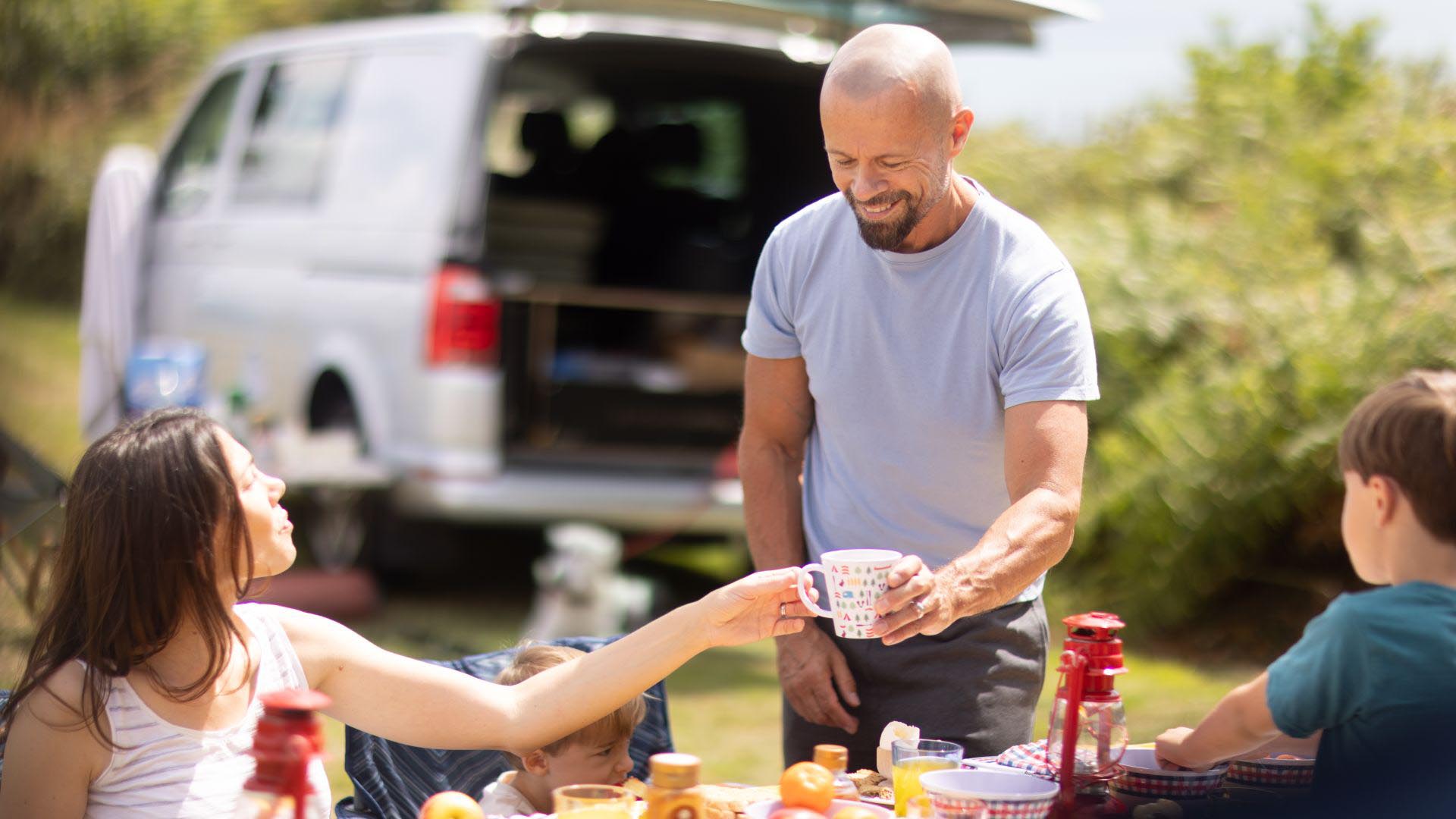 Family sat around campsite sharing a meal