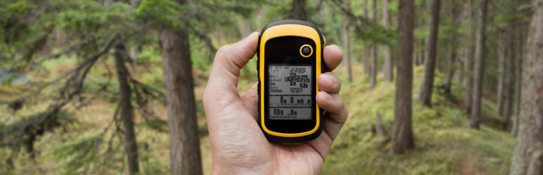 Yellow GPS device being used in the woods