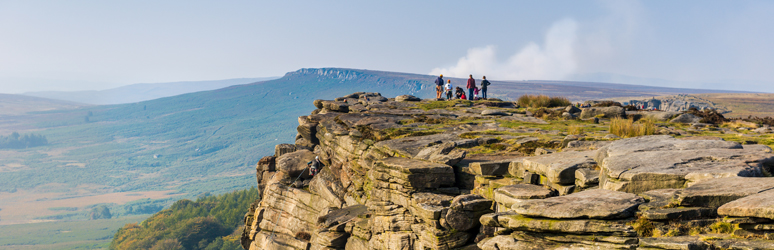 People looking out over Stanage Edge, Peak District