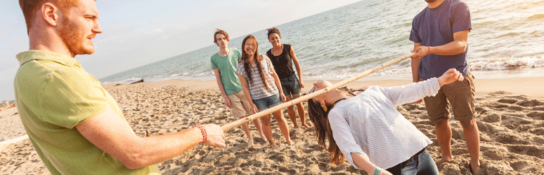 Friends playing the limbo on the beach