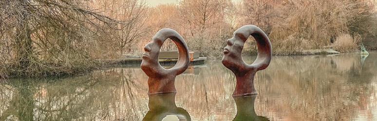 sculpture of heads in a lake