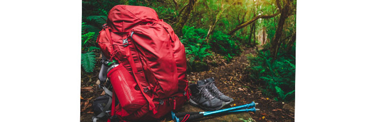 Camping backpack, boots and poles on the ground