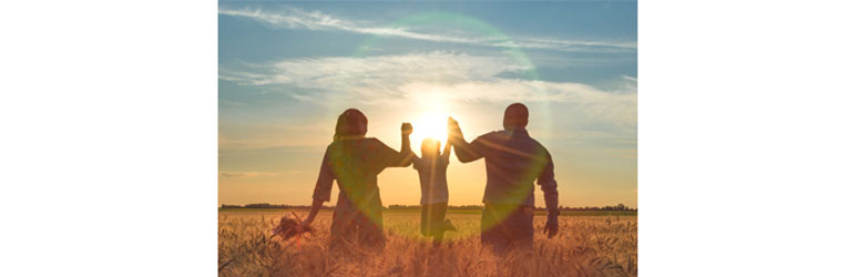 mother and father lifting child up in a field