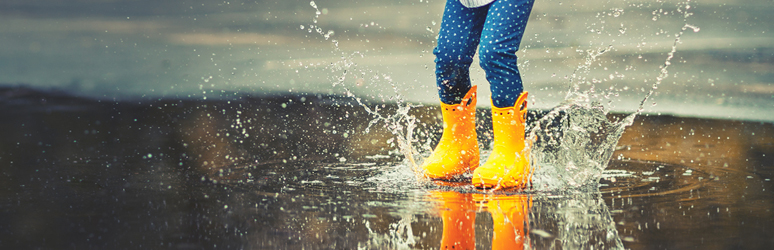 girl splashing in water with yellow wellies 