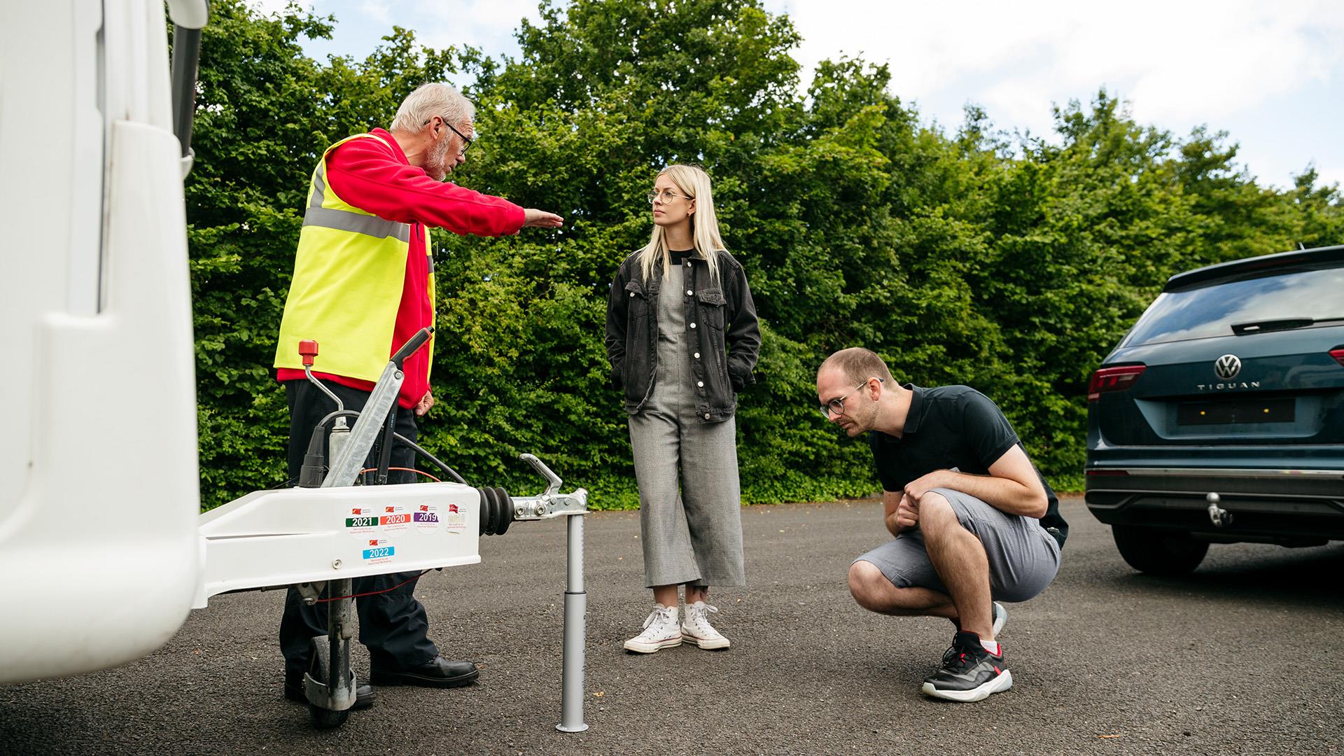 A couple look at a caravan with a towing expert