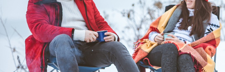 Couple drinking hot drinks outside in the snow