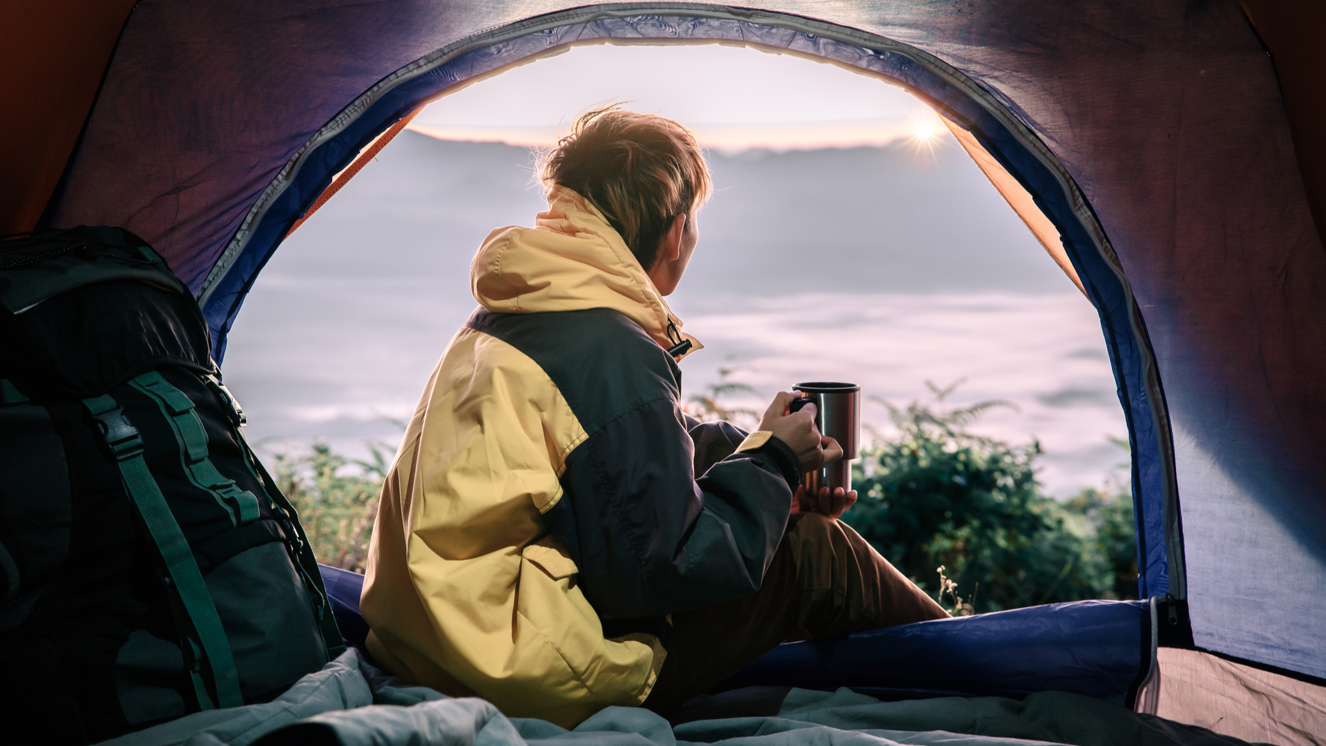 man in a tent looking out into wintry conditions