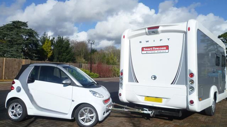 A micro car being towed by a motorhome