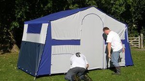 Two men putting up a trailer tent