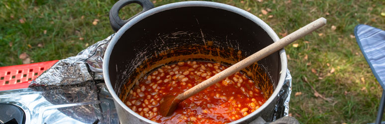 Baked beans cooking in a pot on a campsite