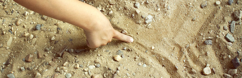 Kid drawing in the sand