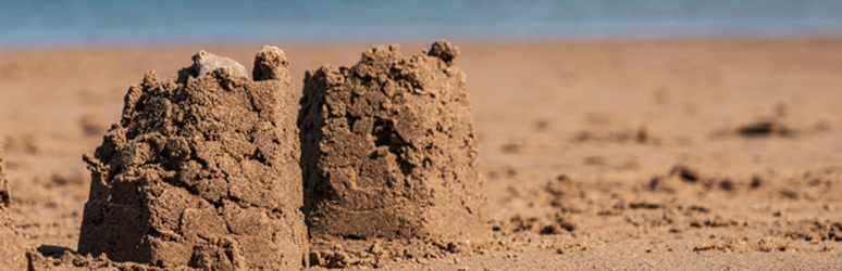 Two sandcastles crumbling on a beach