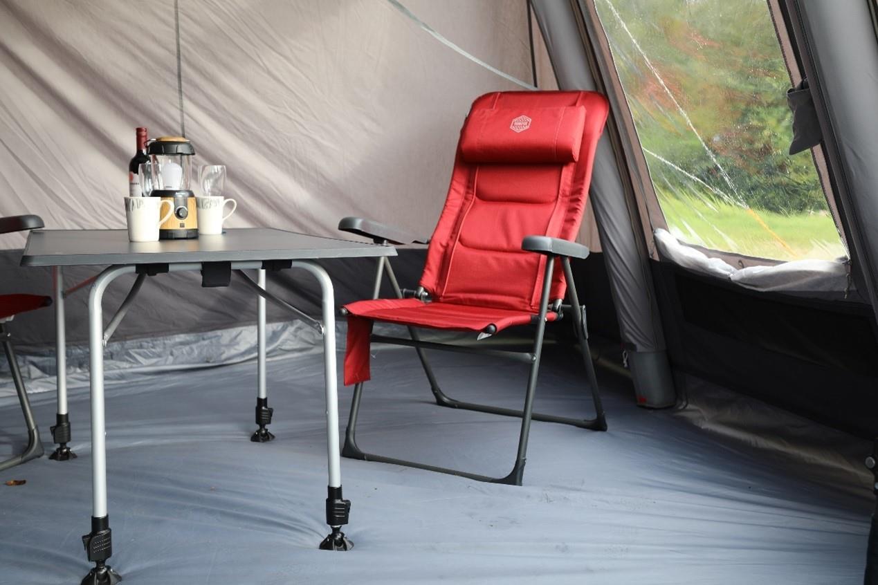 A red heated camping chair placed in a tent next to a camping table