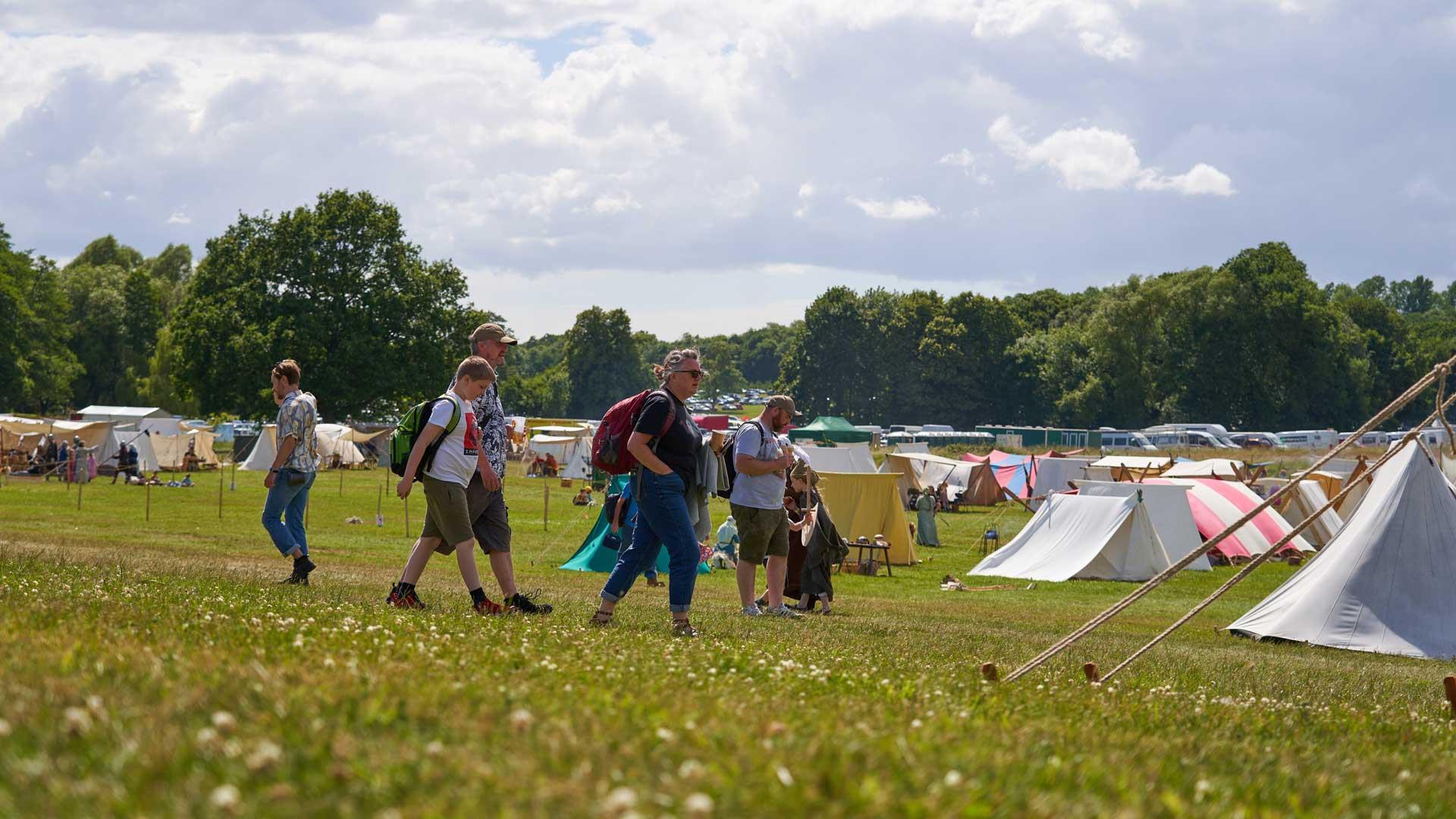 Campers walking in a field of festival tents