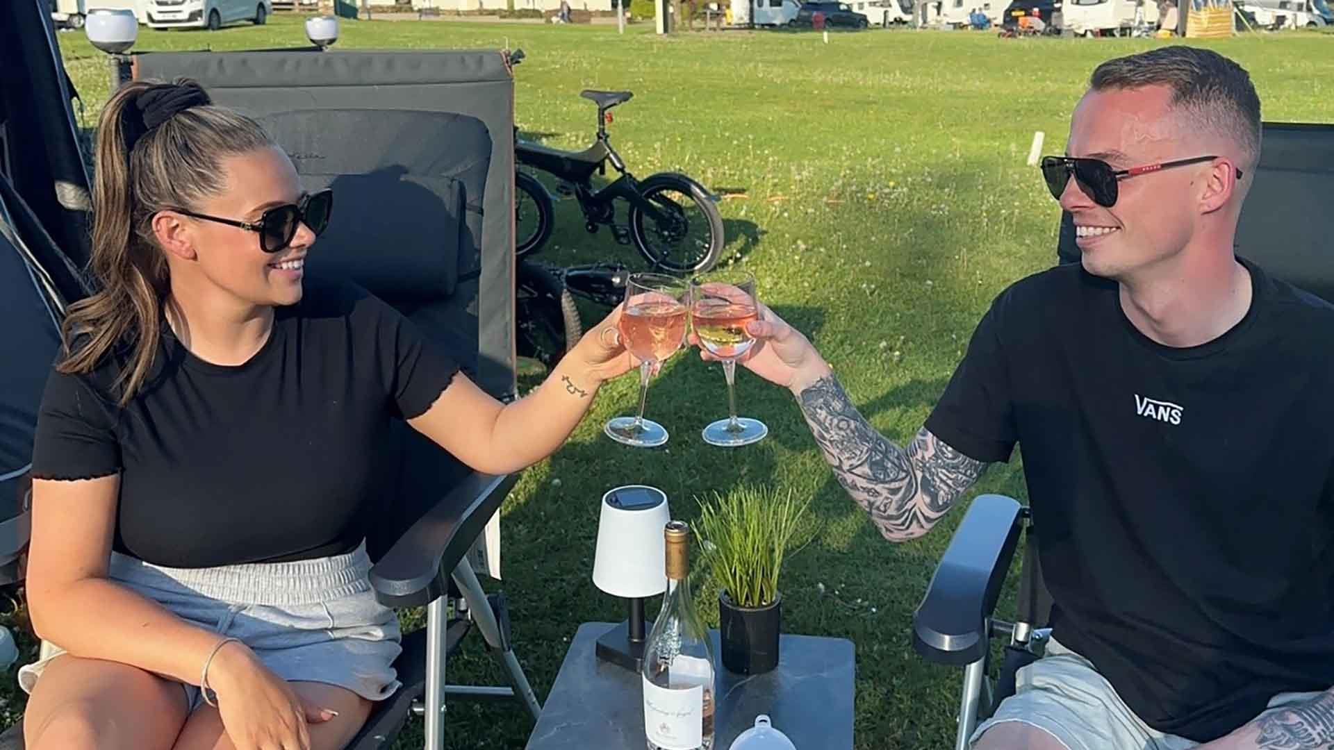 Rebecca Humphrey with friend, Ronnie sitting in deck chairs on a campsite with a glass of wine