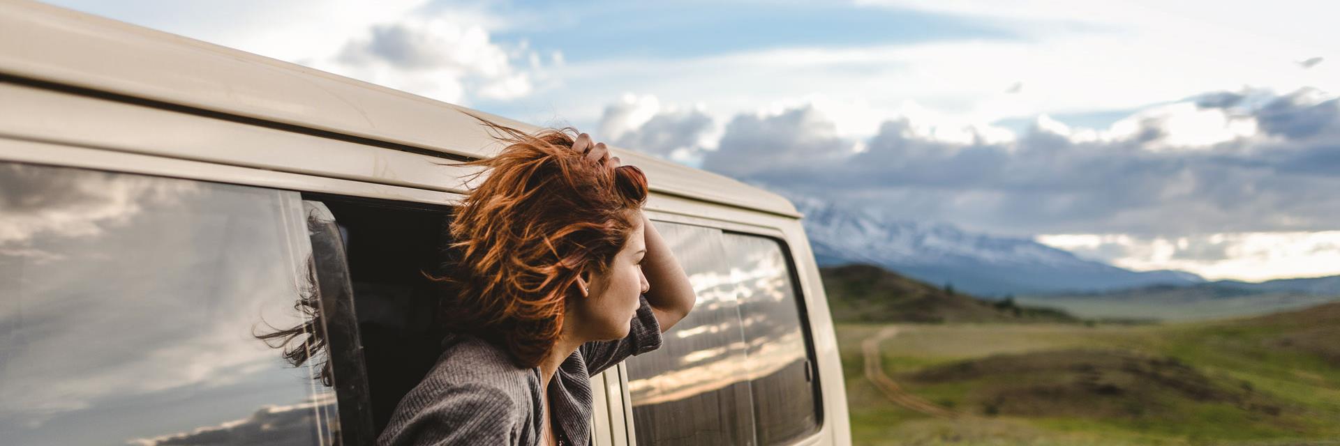 Woman peering out of campervan window.