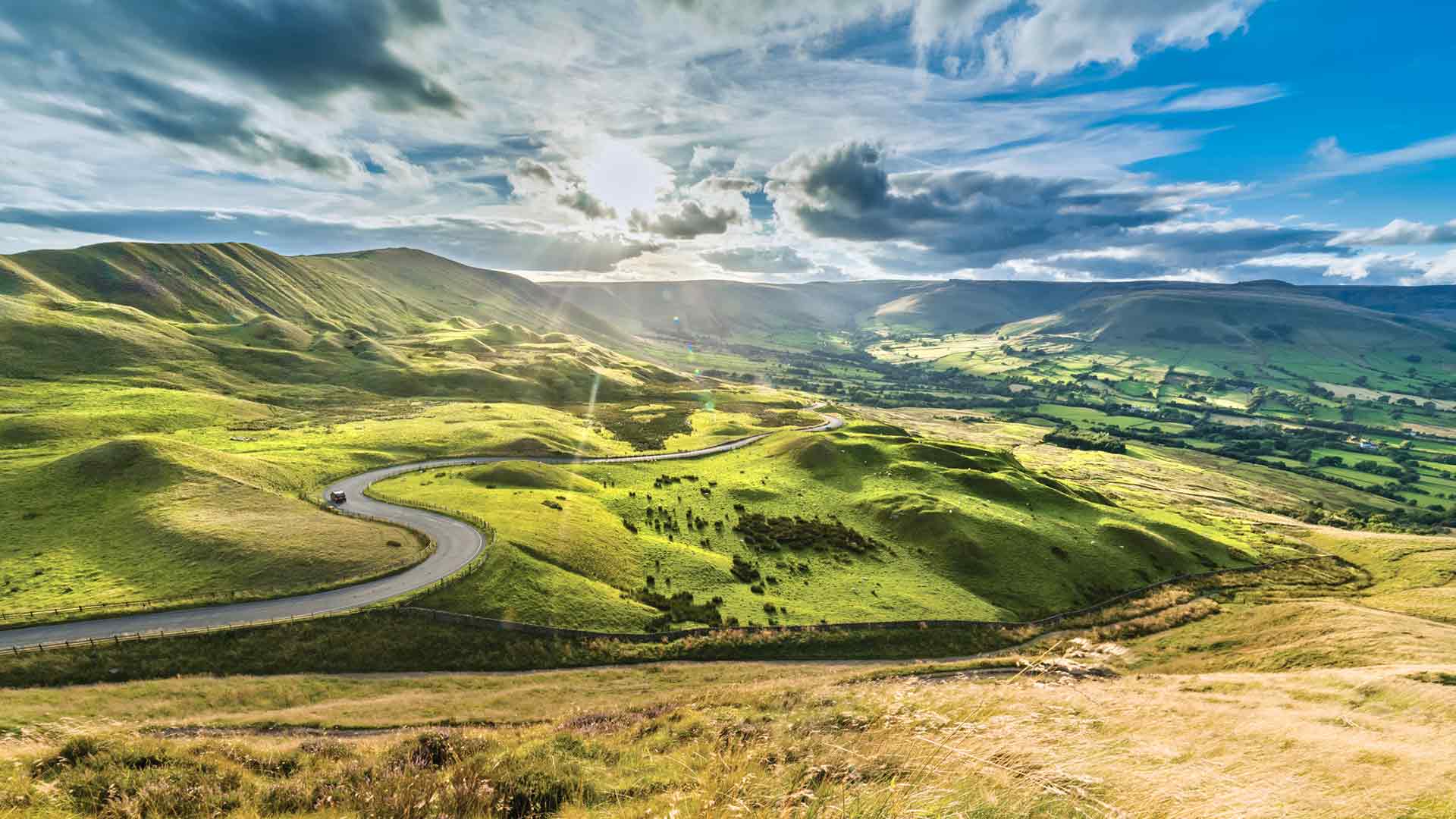 Serpentine Road among green hills of Peak District National Park, England.