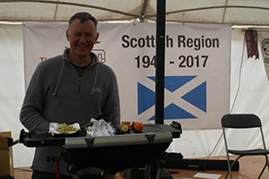 John Johnstone, 2nd placed, busy cooking Tipsy Chicken in front of the Scottish Region 70 Year banner